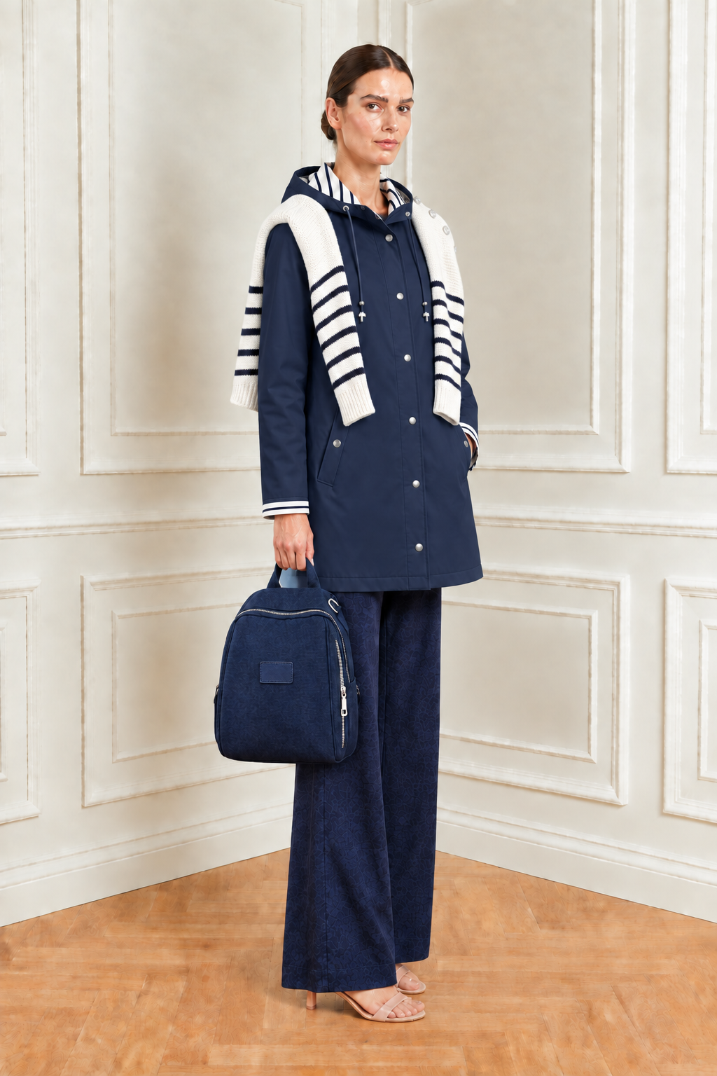 Conjunto con chubasquero azul marino, mochila en la mano y jersey marinero sobre los hombros